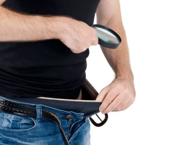 um homem olha para baixo nas calças e quer aumentar o pênis